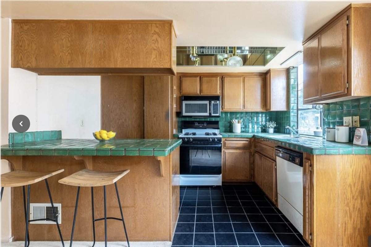 Dated kitchen before renovation — wood cabinets and green tile counters